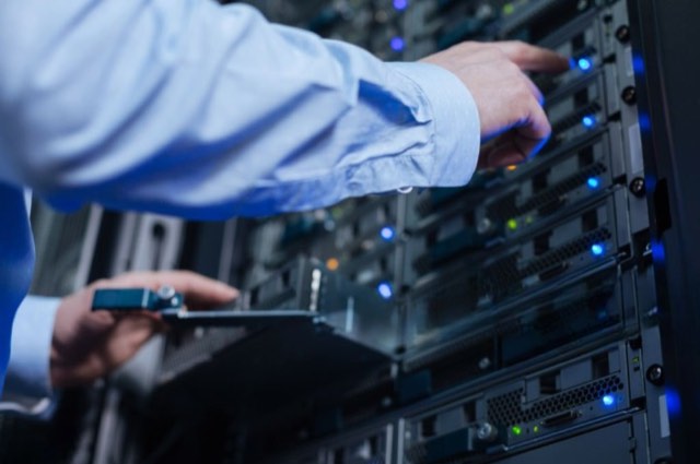Technician installing structured network cabling in a server rack