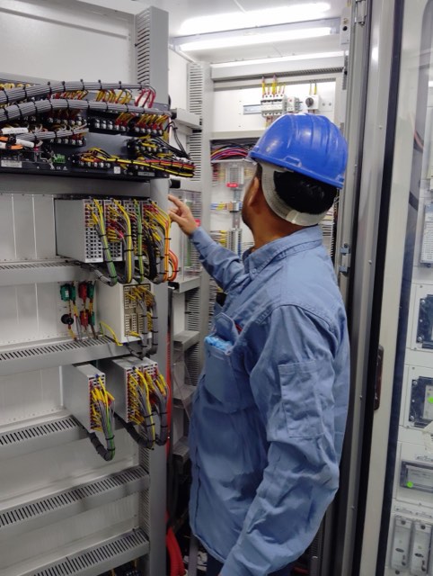 Technician working on an industrial control panel with wiring